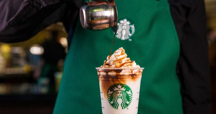 Un trabajador de Starbucks sirve café en un vaso corporativo.