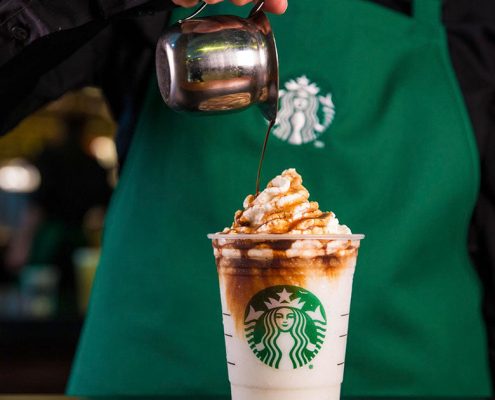 Un trabajador de Starbucks sirve café en un vaso corporativo.